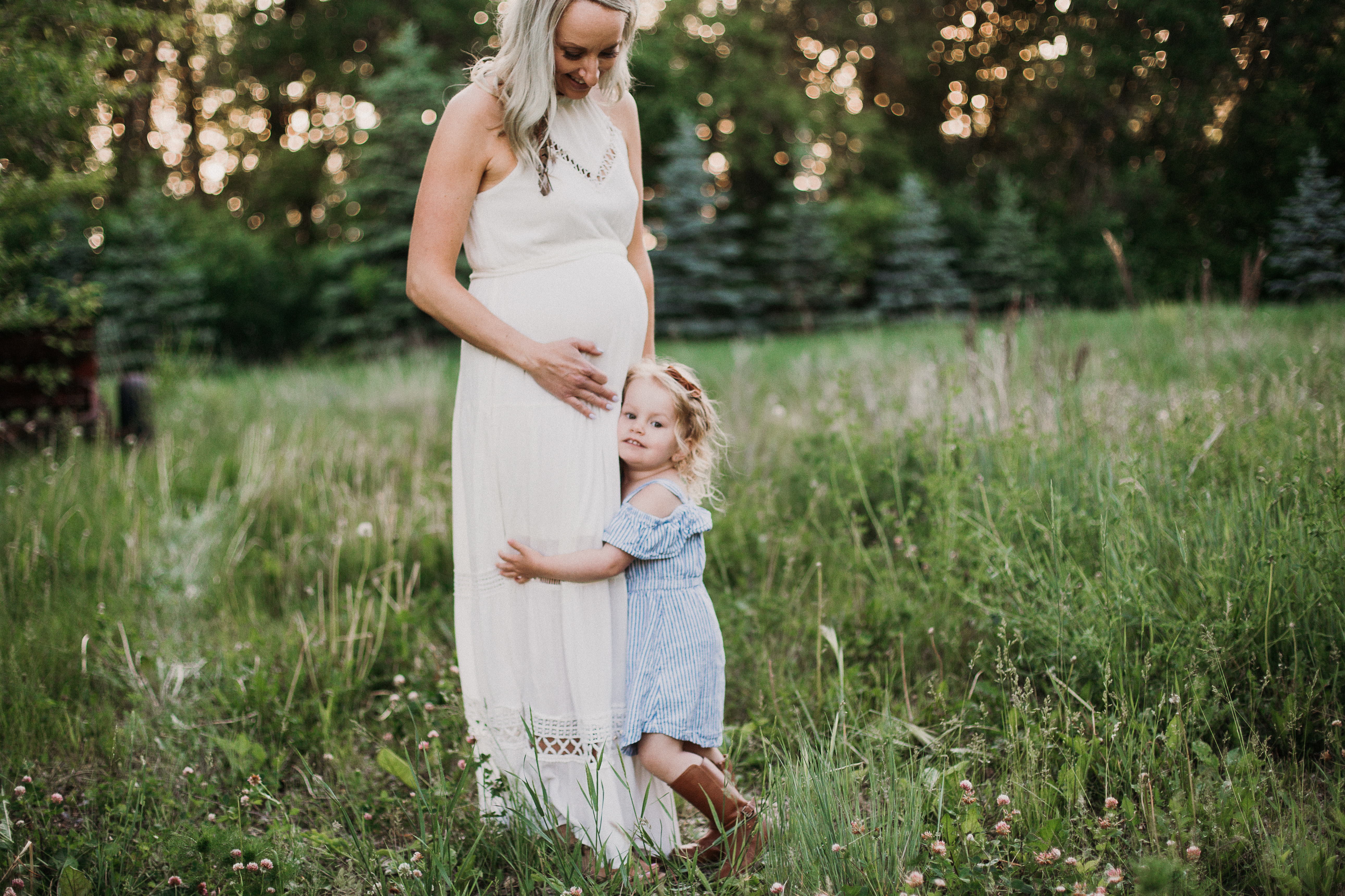 a little girl and her expecting mom in a field in boho dresses