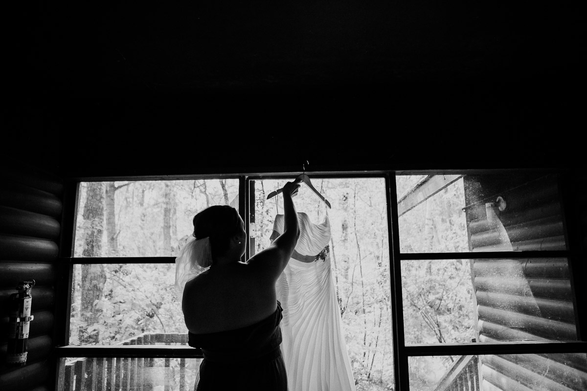 Bride hanging her dress up in the window at Clear Lake Wasagaming Wedding