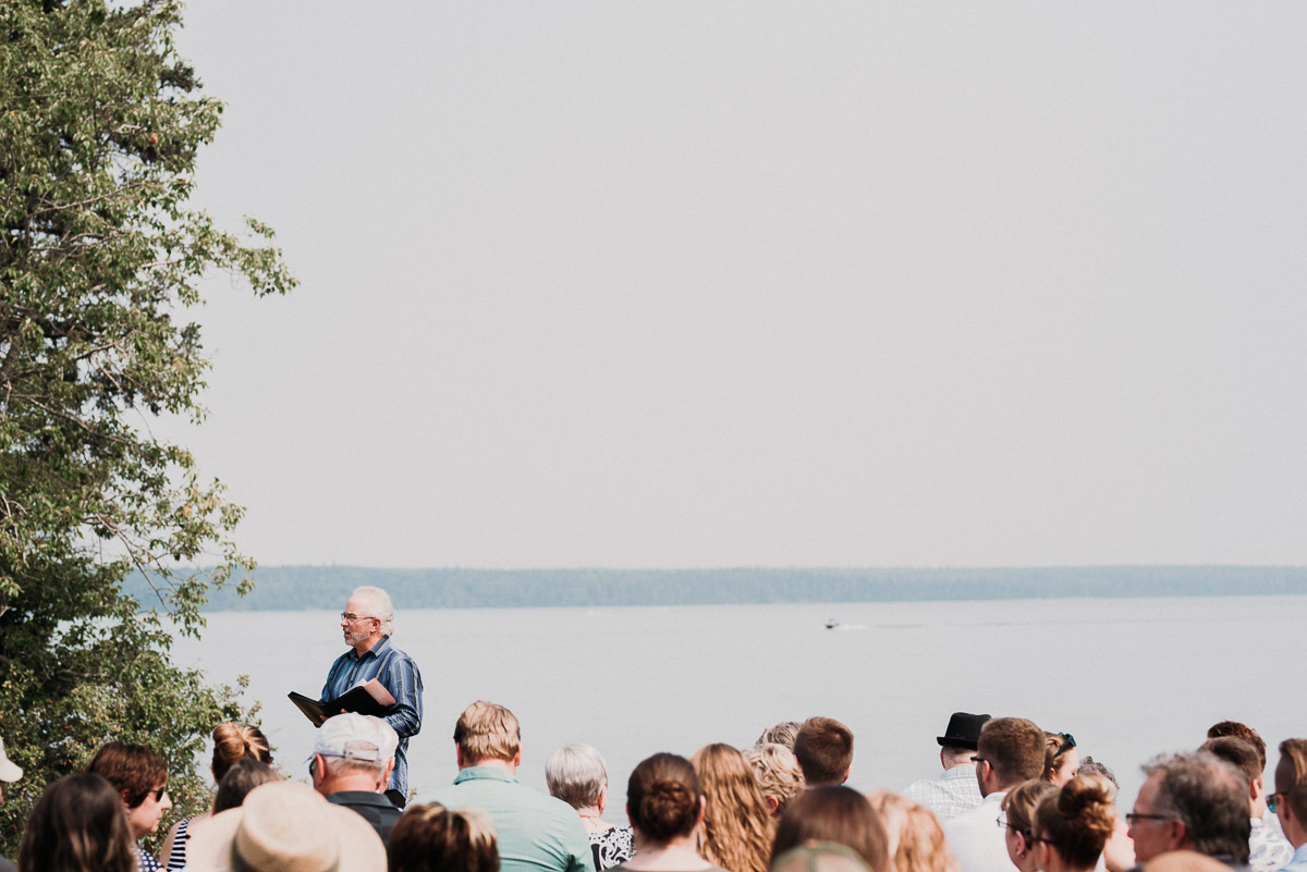 Officiant against the backdrop of a lake at wedding in Riding Mountain National Park