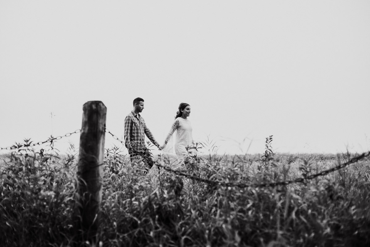 engaged winnipeg couple walking through the field at La Barriere Park