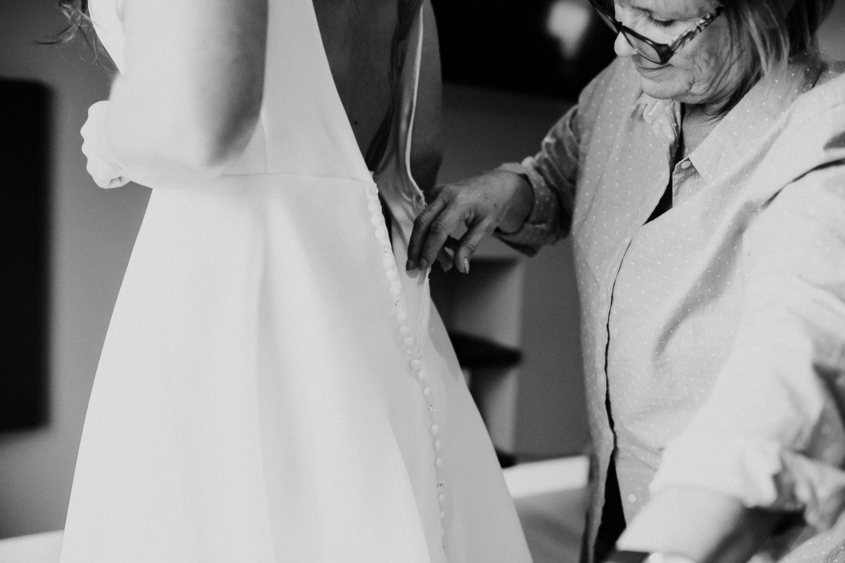 Bride's mother buttoning up her dress on her wedding day